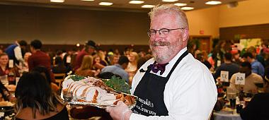 President Green smiles holding carved turkey at the Thanksgiving meal.